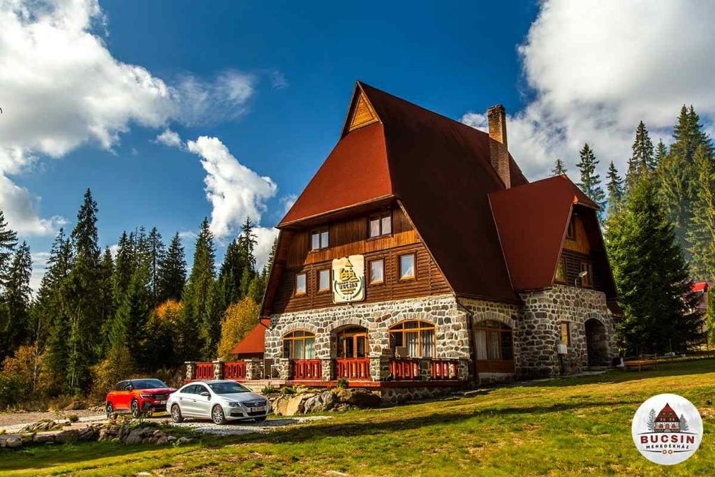 een groot huis met auto's ervoor geparkeerd bij Bucsin menedékház in Bucin