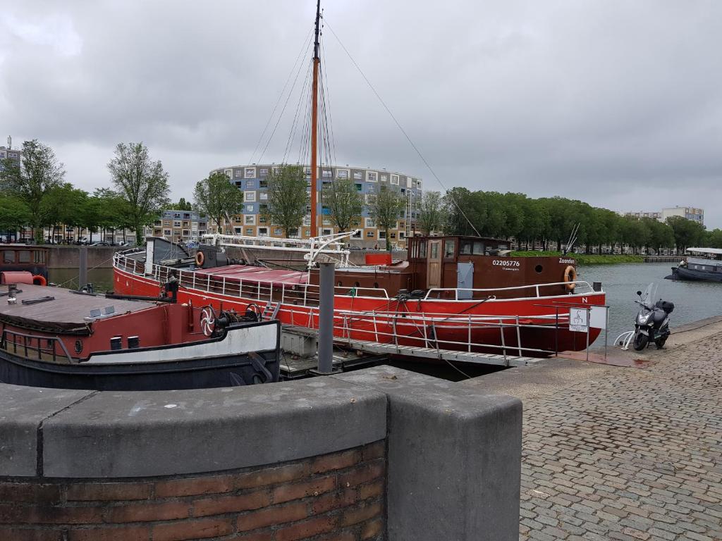 a red boat is docked at a dock at Boat Hotel SIX Rotterdam in Rotterdam