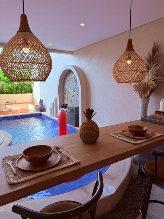 a dining room with a table and a swimming pool at Andara Villa Yogyakarta in Yogyakarta