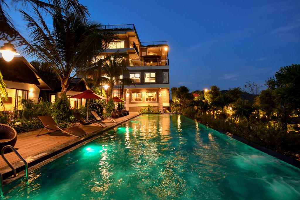 a swimming pool in front of a house at night at San Signature - Suối Ngọc Retreat in Tien Xuan