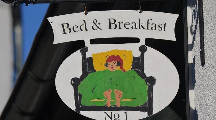 a sign that says bed and breakfast with a person in a chair at Haus Bergzyt -Die Älplersuite, im Ski und Wandergebiet in Linthal