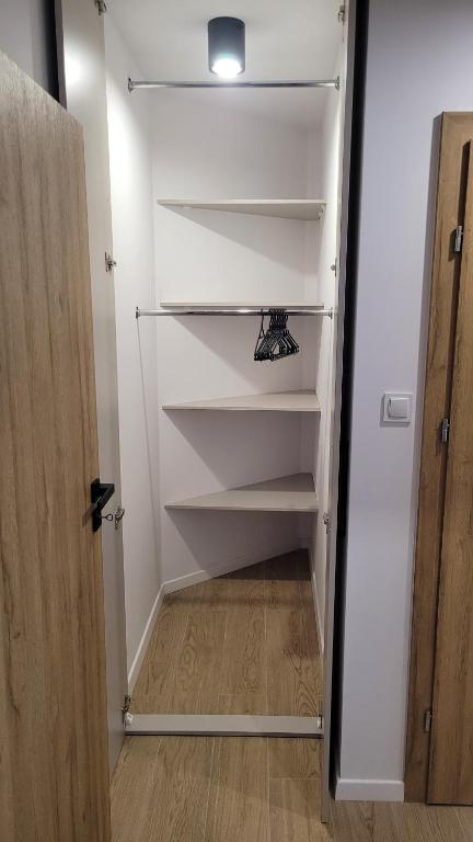 un placard avec des étagères blanches et une porte dans l'établissement Apartament Floriana, à Radom