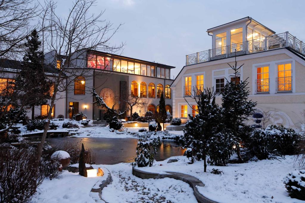uma casa grande com um lago na neve em Garten-Hotel Ochensberger em Sankt Ruprecht an der Raab
