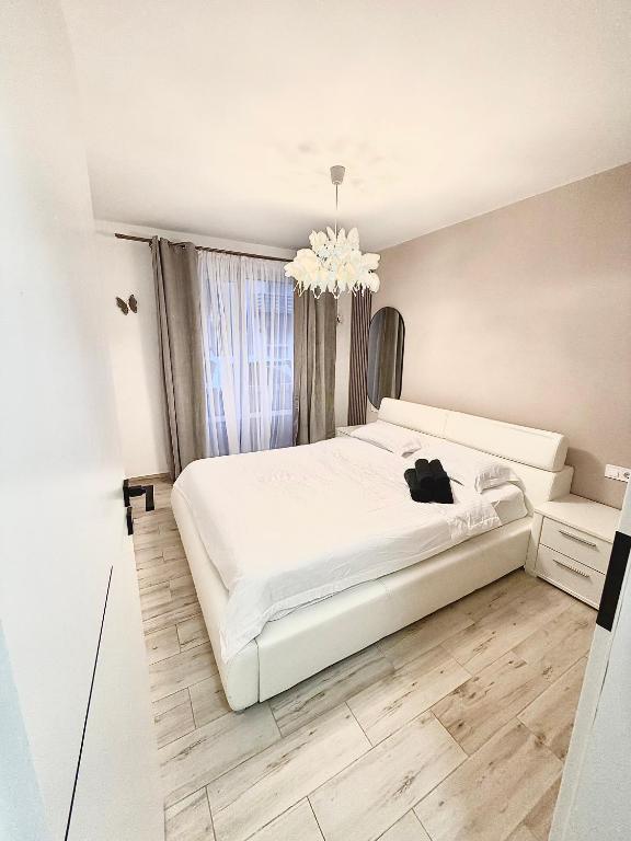 a white bedroom with a white bed and a chandelier at FLH - Obralix Home in Sibiu