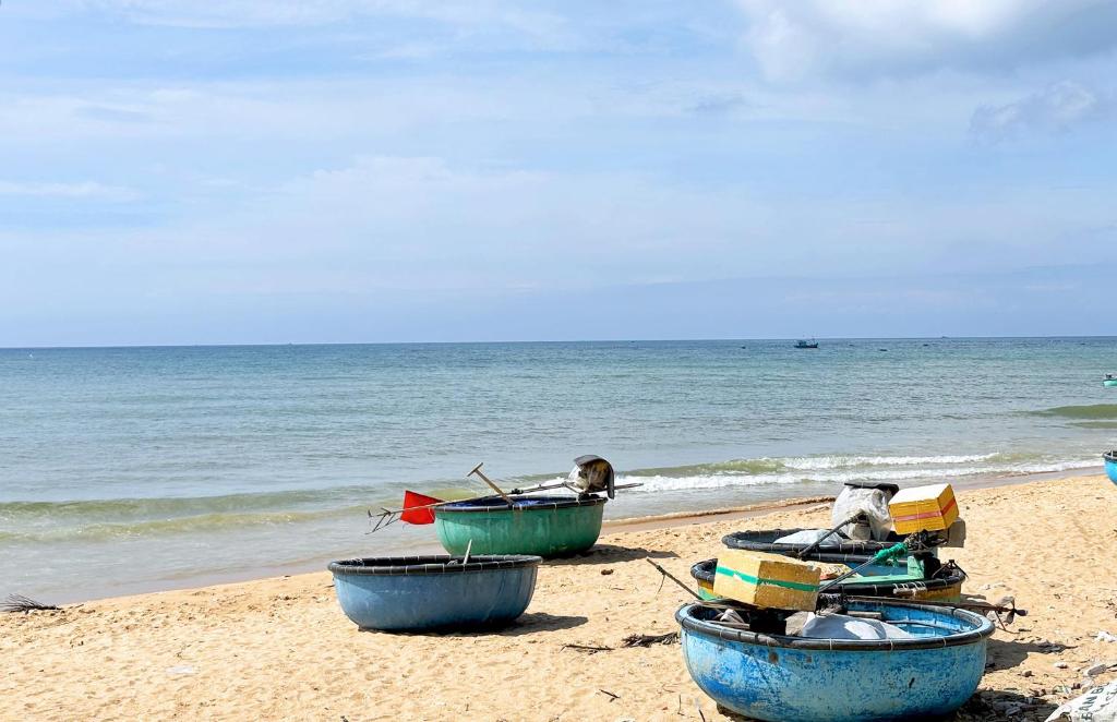 three boats sitting on a beach near the ocean at Villa Biển Vàng Beach Front in Bình Sum