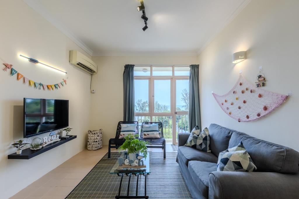 a living room with a blue couch and a tv at EE's Summer House - Homestay 3 min walk to beach in Batu Ferringhi