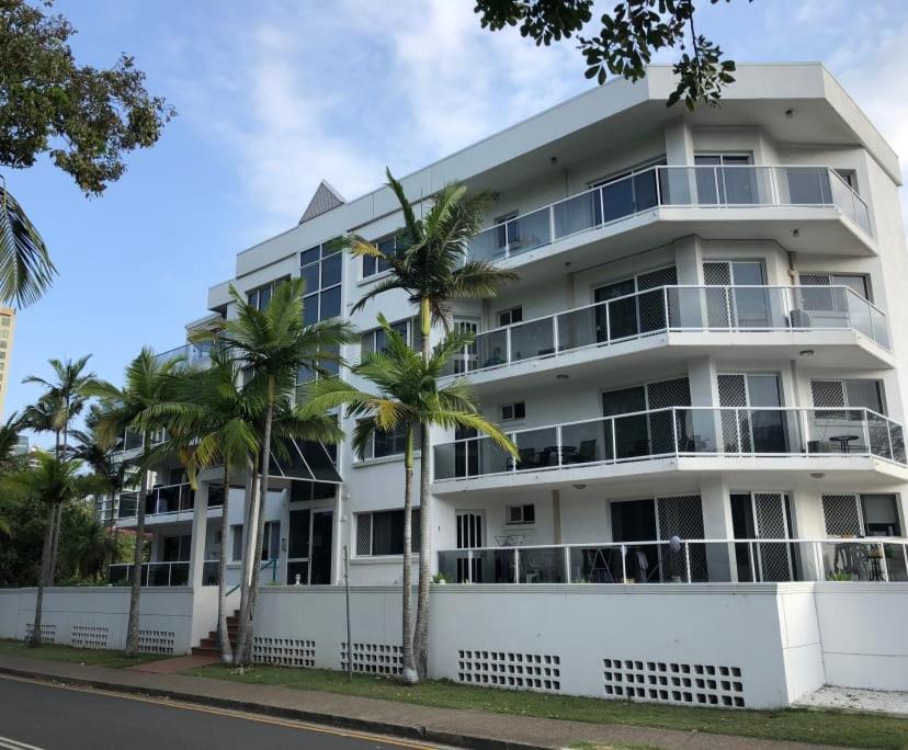 a white building with palm trees in front of it at The Broadbeach Retreat in Gold Coast
