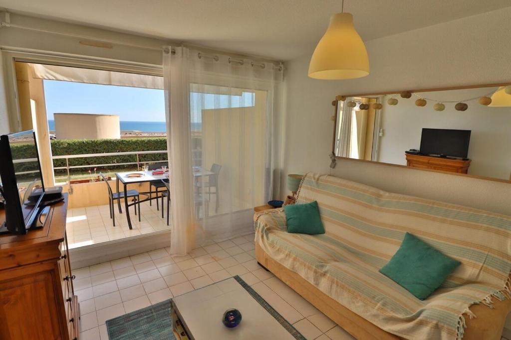 un soggiorno con divano e balcone di Lagune Azur – Séjour cosy vue mer avec Wi-Fi a Sète