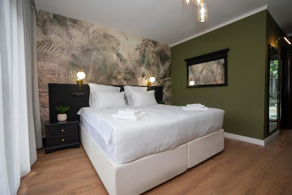 ein Schlafzimmer mit einem großen weißen Bett und grünen Wänden in der Unterkunft Private garden room by MANAGR in Timisu de Jos