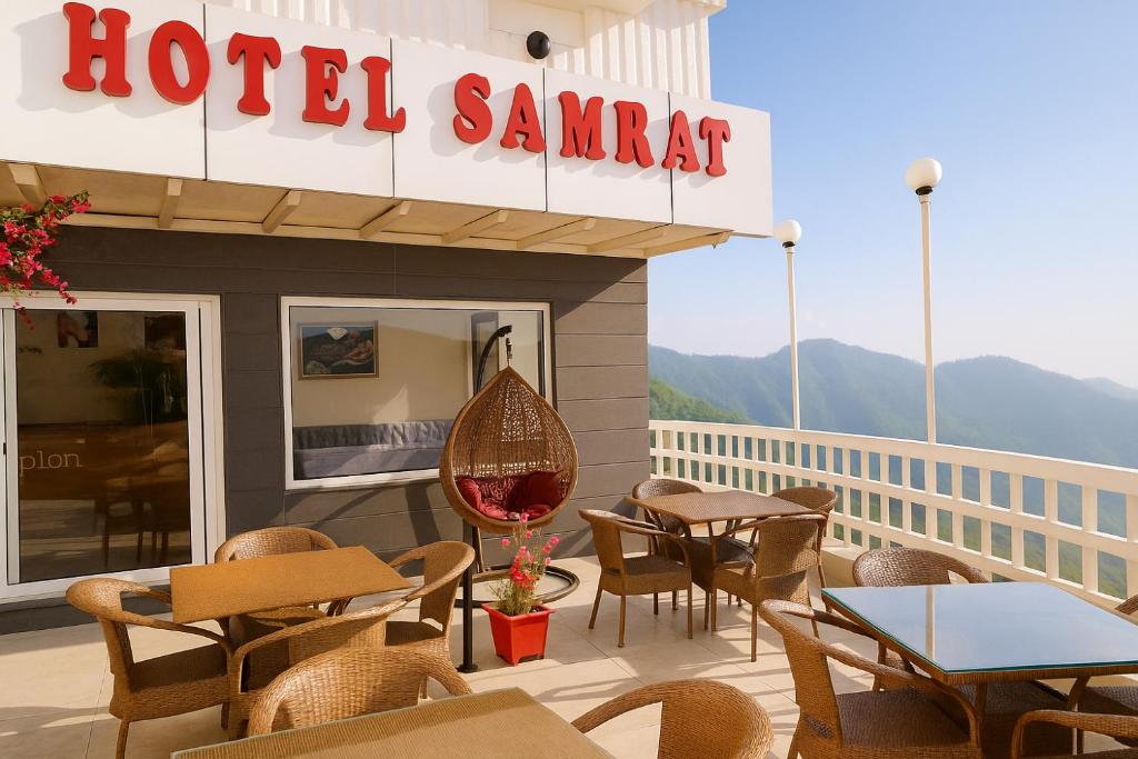 a hotel restaurant with tables and chairs on a deck at Hotel Samrat - On Mall Road in Mussoorie