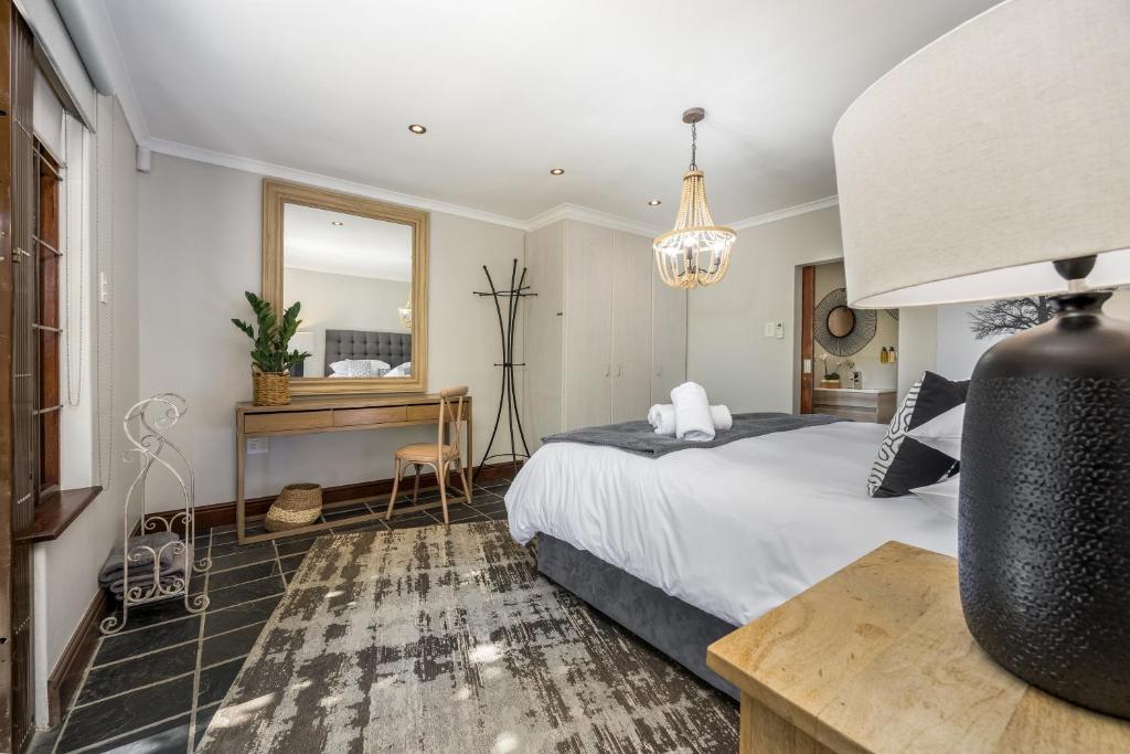 a bedroom with a bed and a desk and a mirror at Avemore Time Out - full power back up in Stellenbosch
