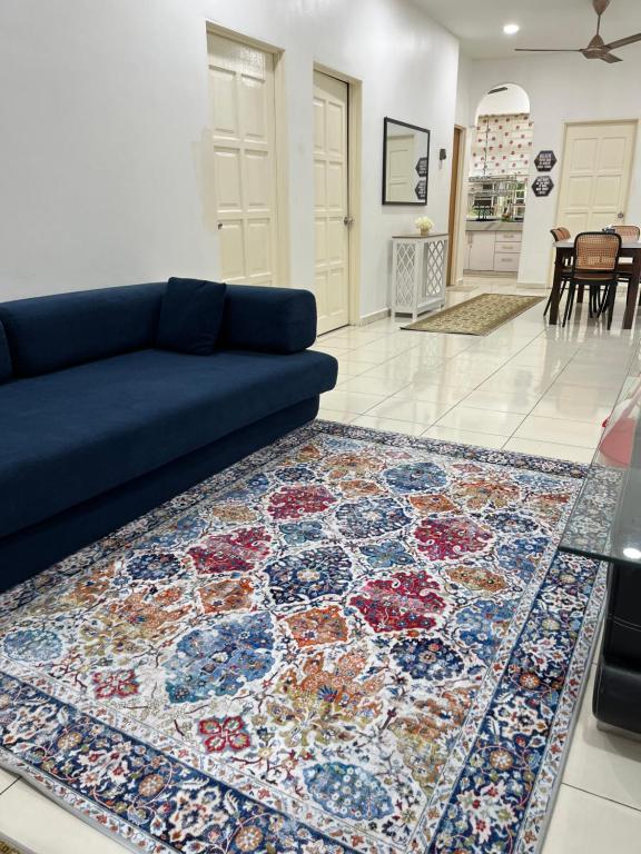 a living room with a blue couch and a rug at Magnolia 3 Homestay in Kampung Raja