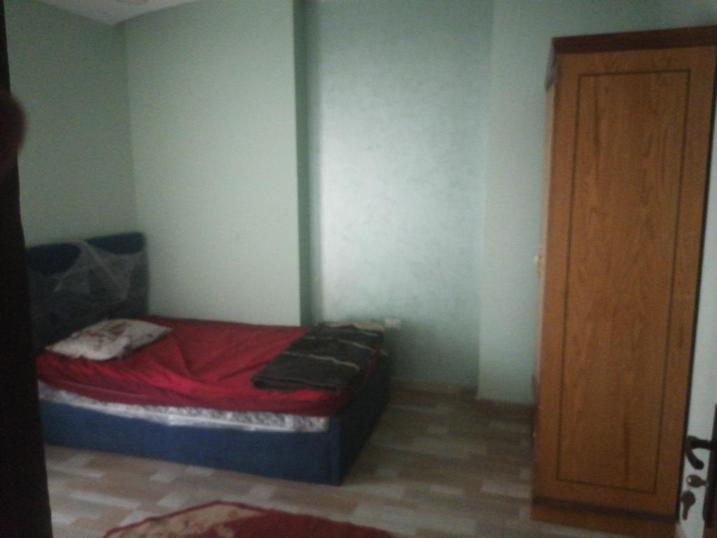 a small bedroom with a bed with red sheets and a door at 8ش ابو بكر الصديق فلل الجامعه الزقازيق in Kafr al Ishārah