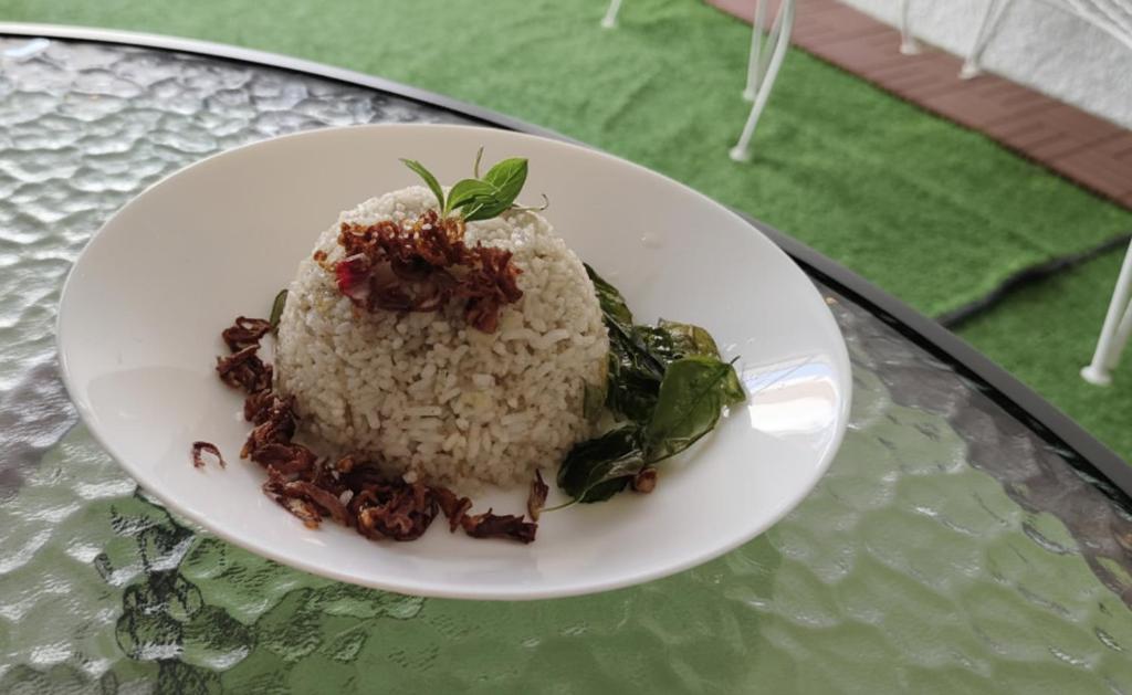 une assiette de riz et de légumes verts sur une table dans l'établissement Thai Nee Homestay, à Manille