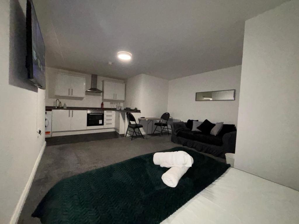 een woonkamer met een bank en een witte kruk bij Cosy Modern Studio Apartement in Ilkeston