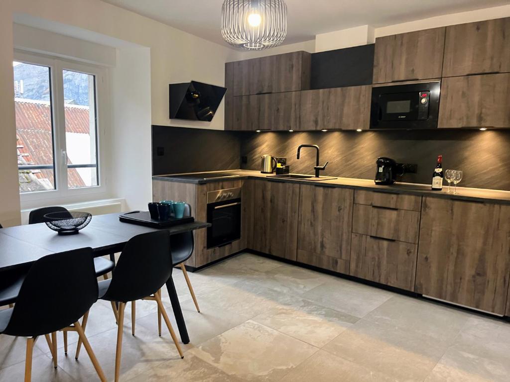een keuken met houten kasten en een tafel en stoelen bij Le Vieux Bourg Apartment 2 in Le Bourg-dʼOisans