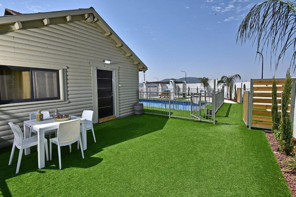 a patio with a table and chairs on the grass at אחוזת אודליה במושב דלתון in Shahar