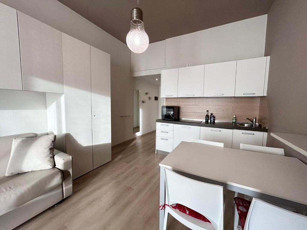 a kitchen with white cabinets and a table and chairs at Rucola Home in Castione della Presolana