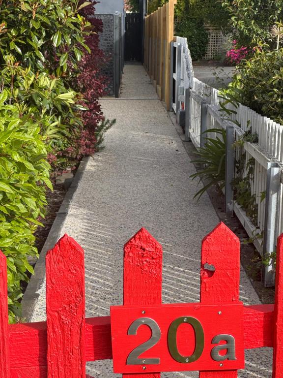 a red gate with a sign next to a sidewalk at Little Red Gate Urban Retreat in Kingston