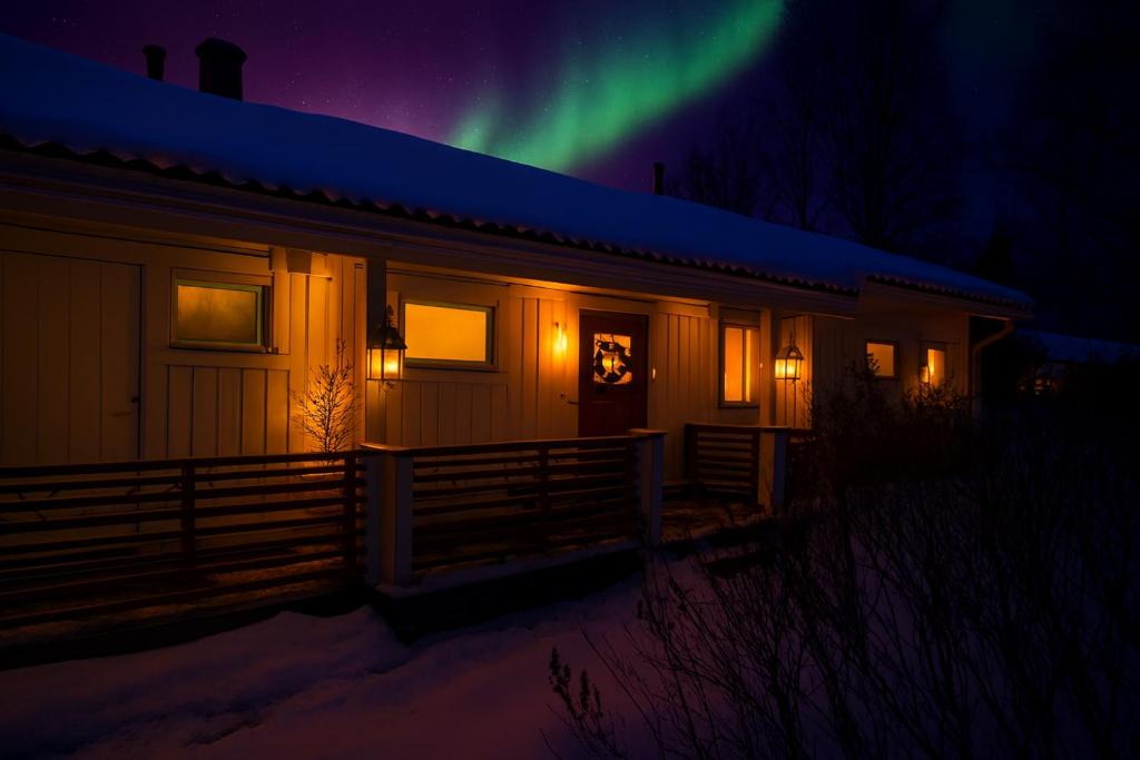 a house with the aurora in the sky at Rovaniemi Riverside Family House near Santa Claus Village - Sauna & Aurora View in Rovaniemi