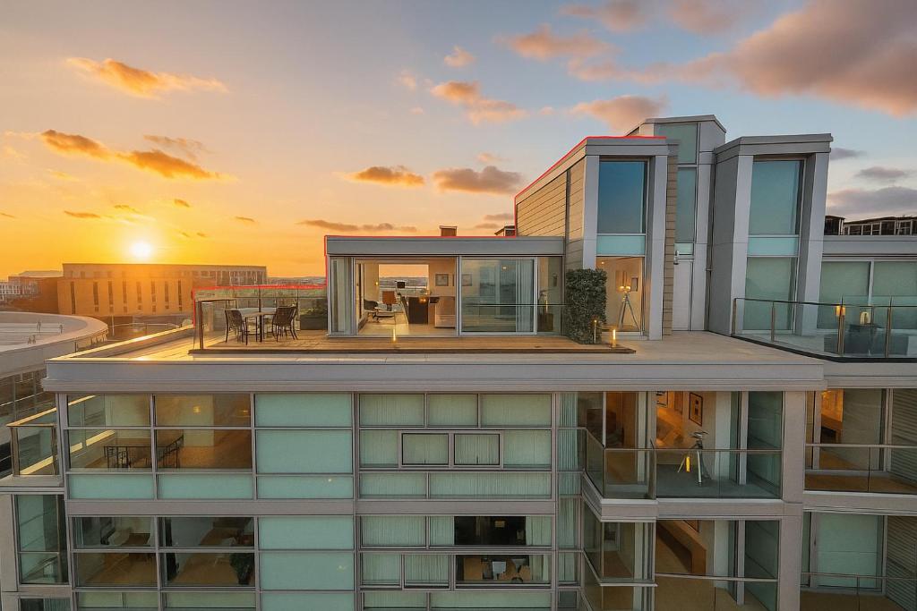 Sidemersey Livings- Unmatched Panoramic Views, Secure Parking, Beautiful Balcony- A Stay to Remember في ليفربول: مبنى مع غروب الشمس في الخلفية