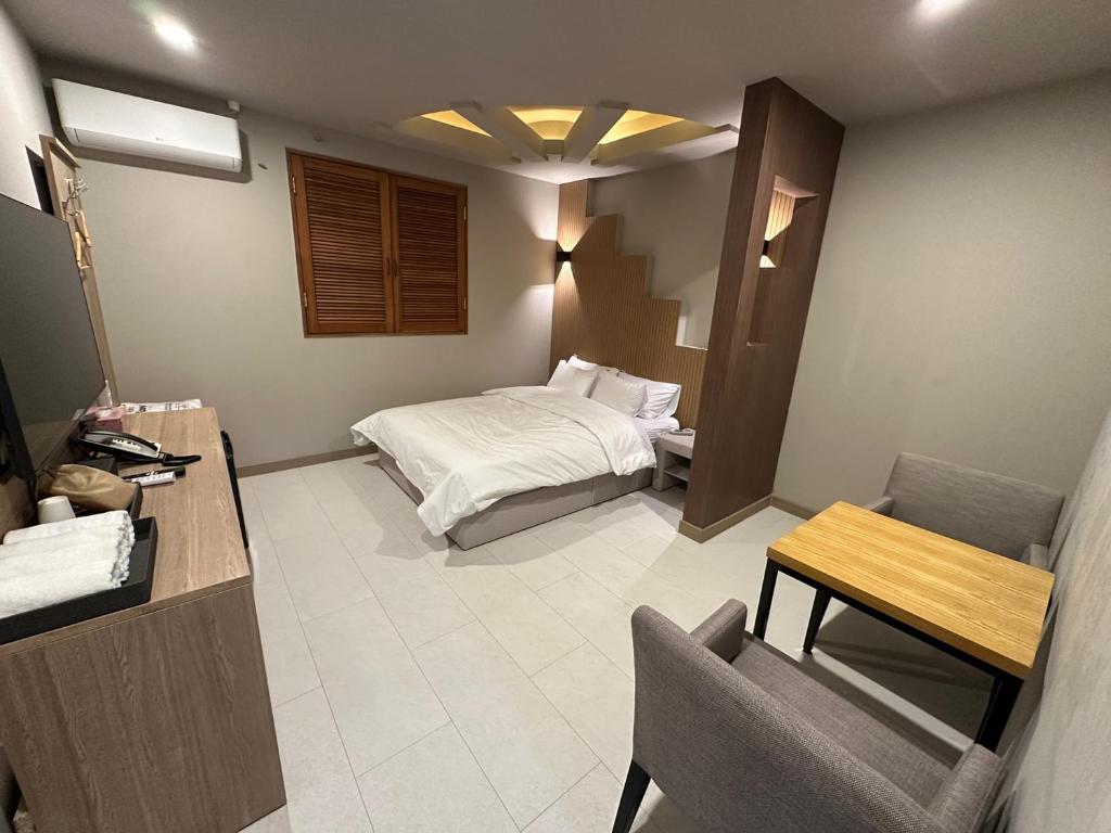 a bedroom with a bed and a table and a chair at 계룡 호텔 스테이318 in Gyeryong