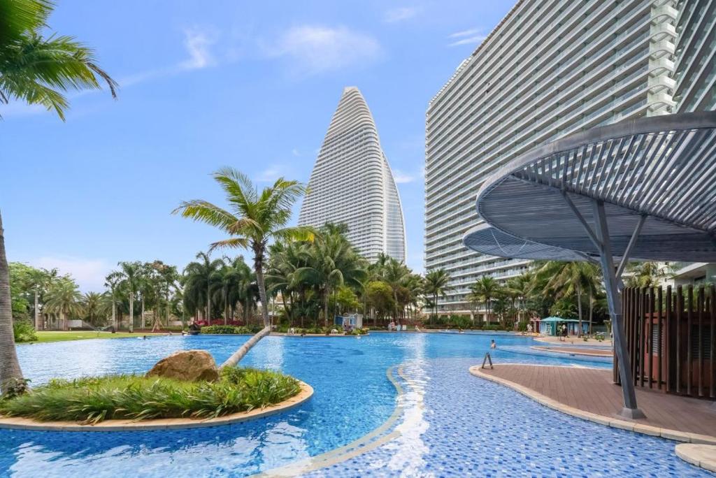 a pool in front of two tall buildings at 来咖民宿酒店三亚海棠湾亚特兰蒂斯棠岸店 in Fengtang