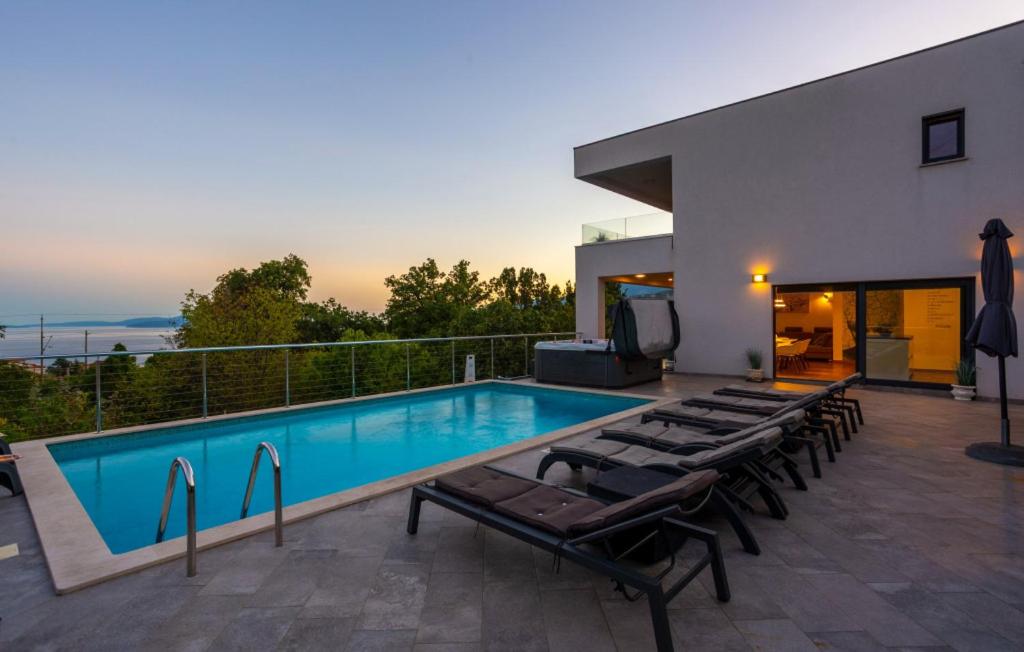 a swimming pool with lounge chairs next to a house at Villa Angello in Matulji