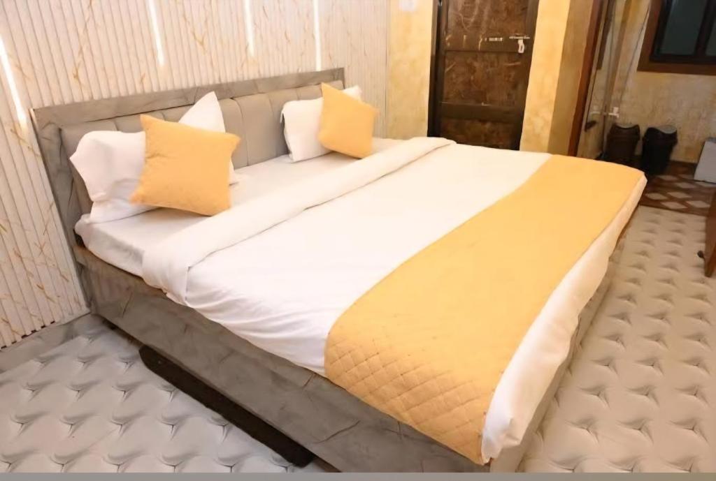 Una cama grande con dos almohadas amarillas encima. en Sawaria Residency, en Varanasi