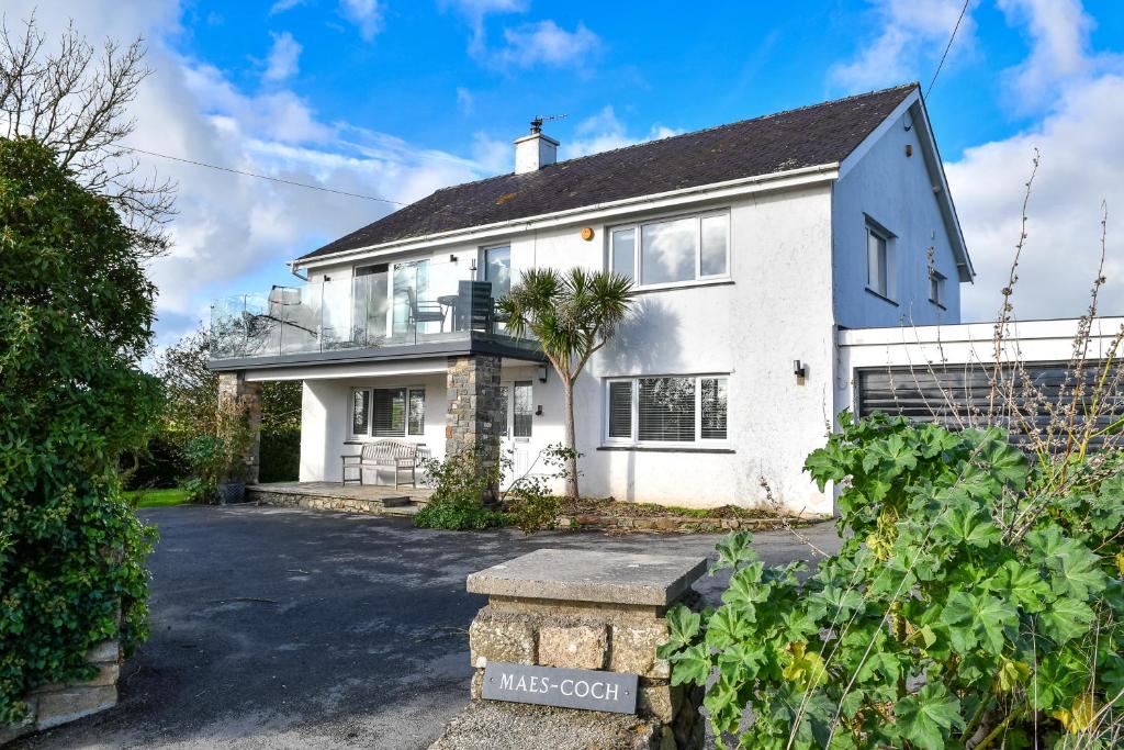 a white house with a palm tree in the driveway at Maes Coch in Abersoch