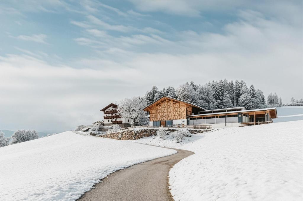 a house on a snow covered hill with a road at Untermathonhof Vöran - Apartments with homemade Breakfast in Verano
