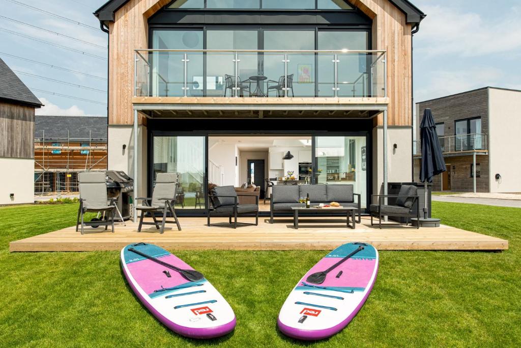 zwei Surfbretter sitzen auf dem Gras vor einem Haus in der Unterkunft Brightside SV35 Silverlake Dorset in Warmwell
