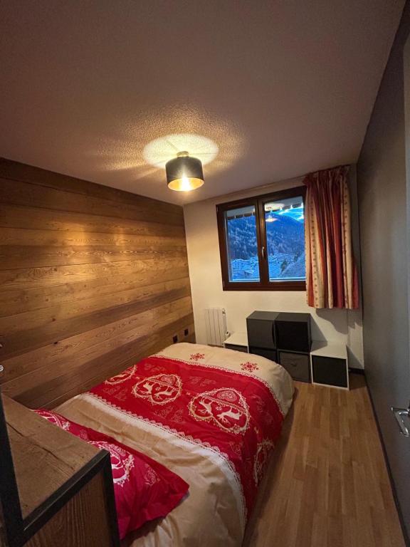 ein Schlafzimmer mit einem Bett mit einer roten Decke in der Unterkunft Appartement cosy quartier Napoléon in Val Cenis
