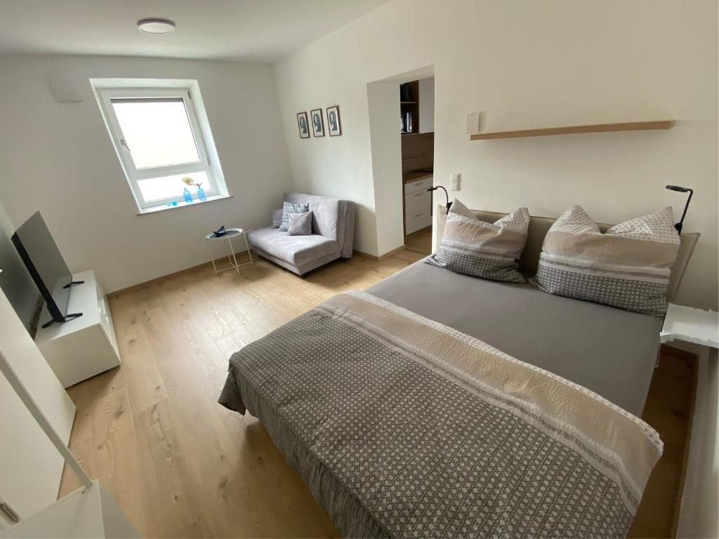 a bedroom with a bed and a chair and a window at kreuzwirt bayern in Essenbach