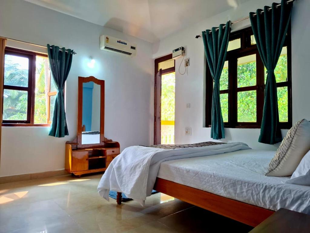 a bedroom with a bed and a mirror and windows at Palolem by Casa de Palmora in Canacona