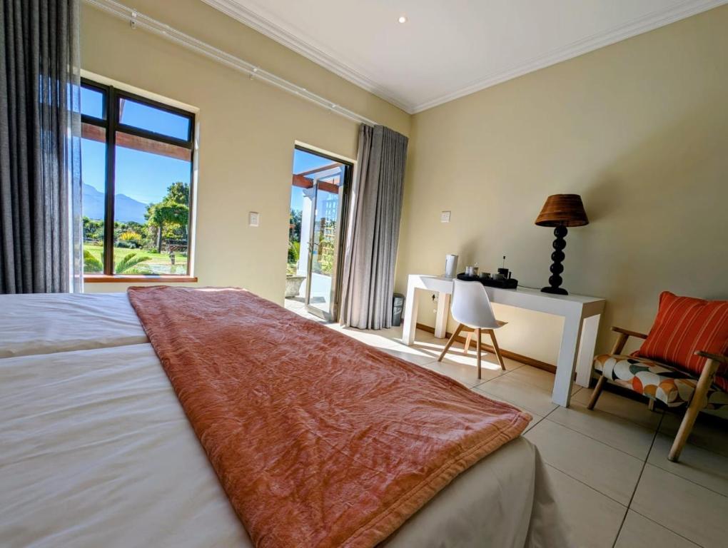 een slaapkamer met een bed, een bureau en een raam bij New Wave Village in George