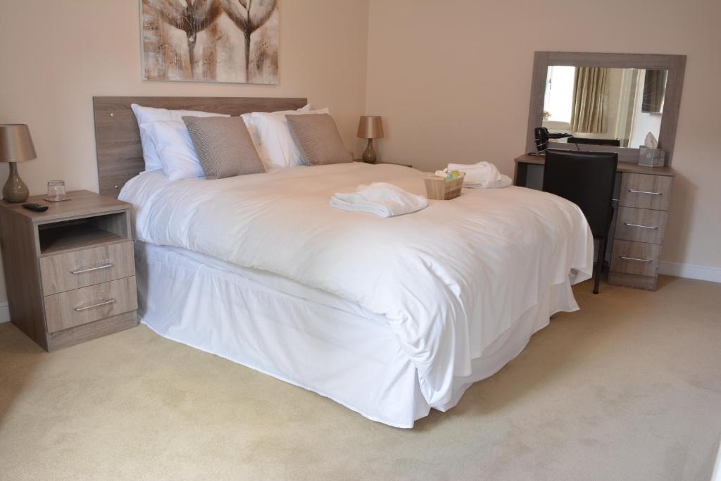 a bedroom with a large white bed and a mirror at Greyhound Inn in Winterborne Kingston