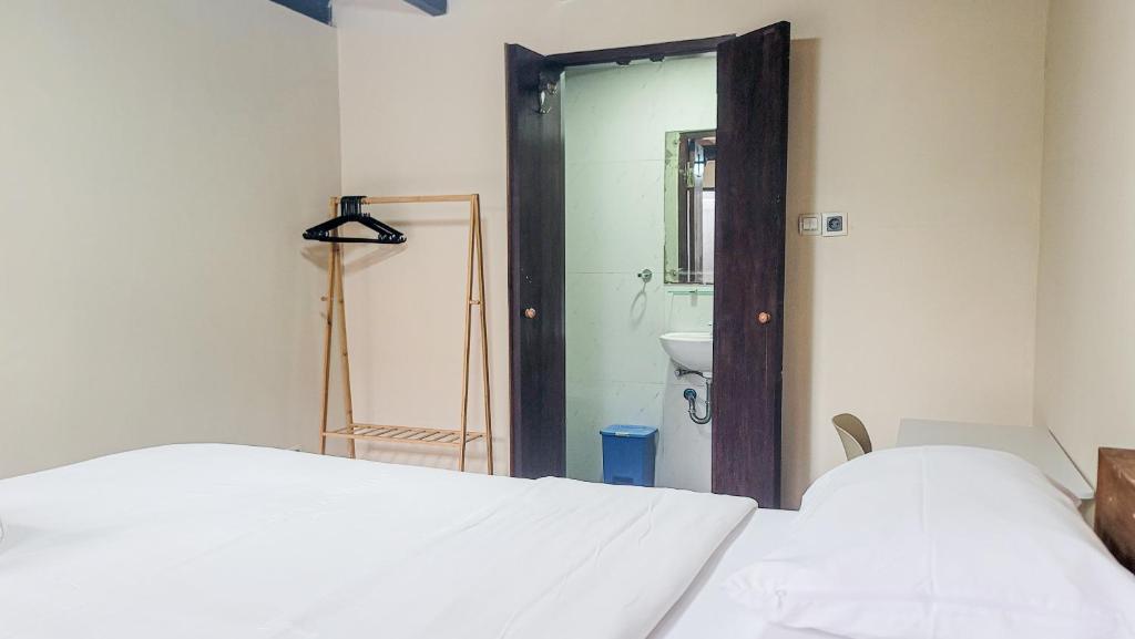a bedroom with a bed and a bathroom with a mirror at Capung Guesthouse in Jimbaran