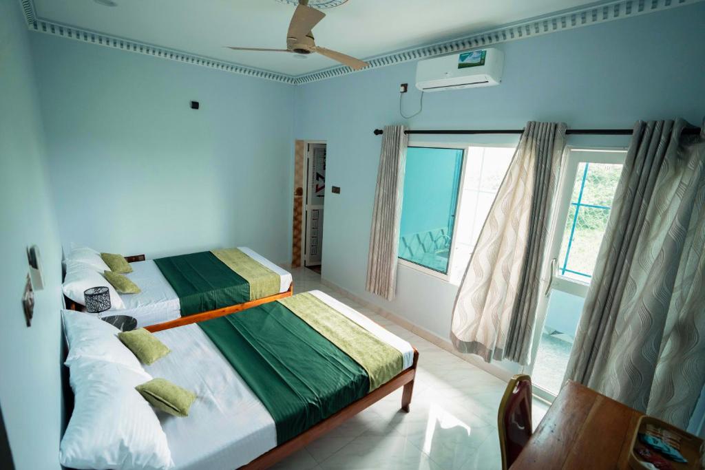 een slaapkamer met twee bedden en een raam bij Best Inn in Jaffna