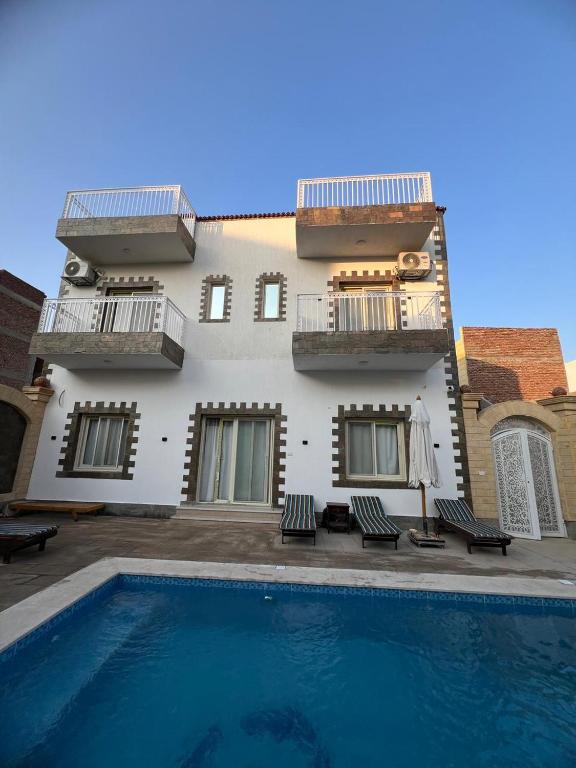 a villa with a swimming pool in front of a building at Twins Villa Luxor in Luxor