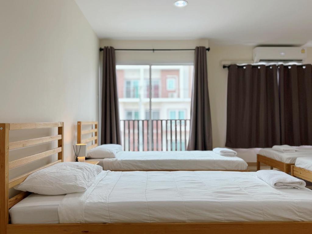 three beds in a room with a window at Jira cozy room Suvarnabhumi Airport 15mins in Lat Krabang