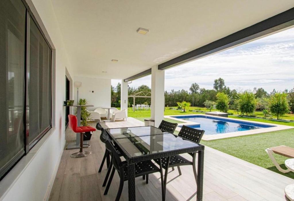 a dining room with a glass table and a swimming pool at OLE TÚ ANDALUCIA in Sanlúcar la Mayor