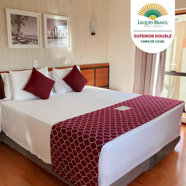 a bedroom with a large bed with red pillows at Leques Brasil Hotel Escola in São Paulo