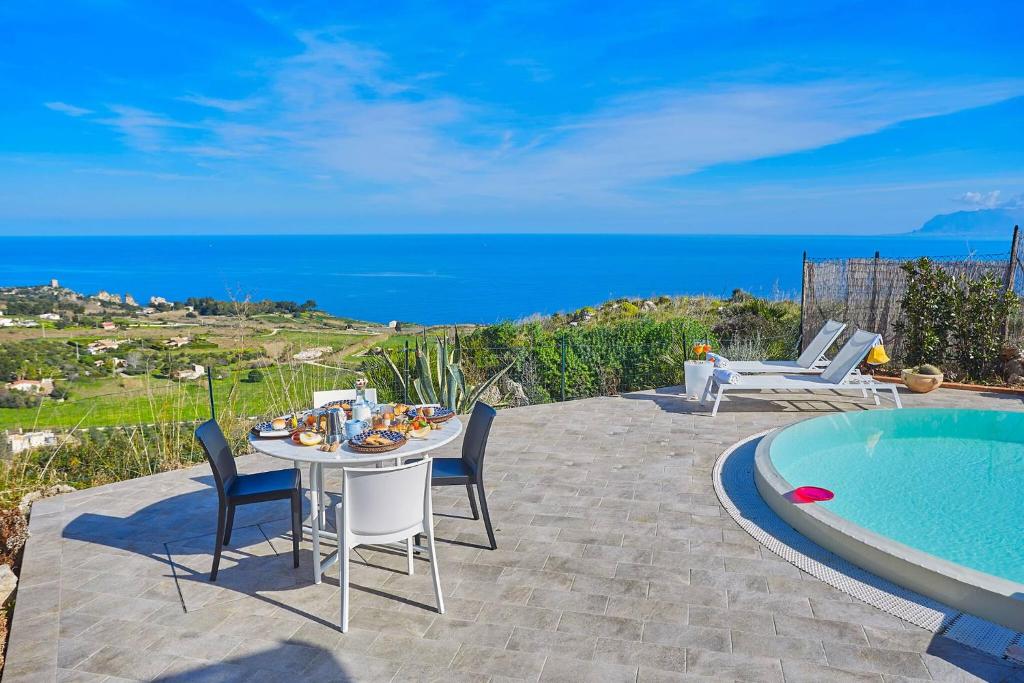 un patio avec une table et des chaises à côté d'une piscine dans l'établissement Villa Tarì, à Scopello