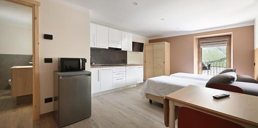 a bedroom with a bed and a kitchen with a table at Ca del Tusa in Livigno