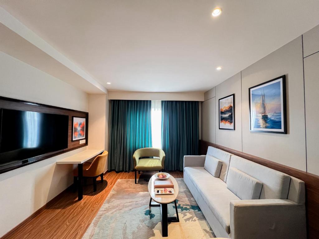 Una sala de estar con un sofá y un televisor en Tulip Inn Bhopal, en Bhopal
