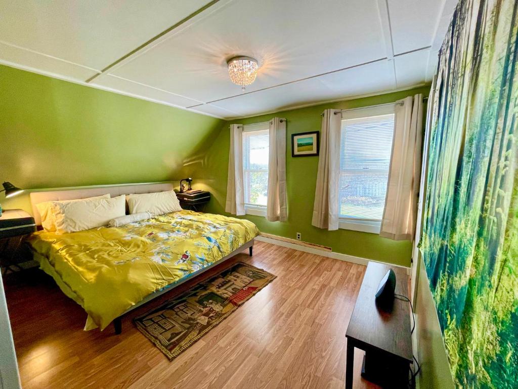 una camera da letto verde con un letto e una finestra di Mattawamkeag River Cottage a Island Falls