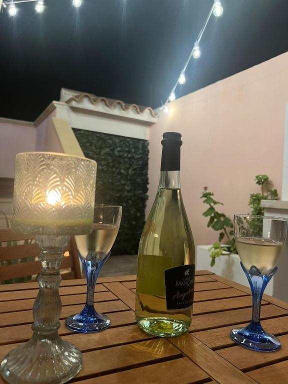 a bottle of wine and two glasses on a wooden table at La Pavoncella Holiday Home in San Vito
