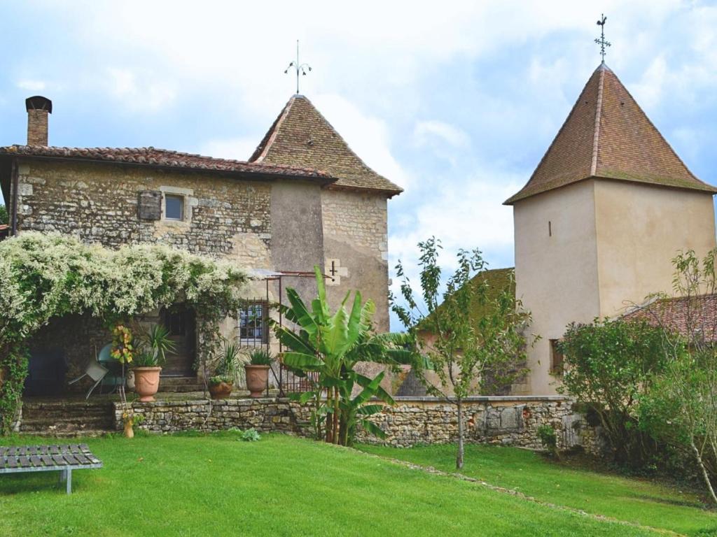 an old stone house with a tower and a yard at Prieuré restauré avec jardin, charme ancien et commodités modernes, près de l’église à Beaulieu - FR-1-653-145 in Beaulieu-sur-Sonnette