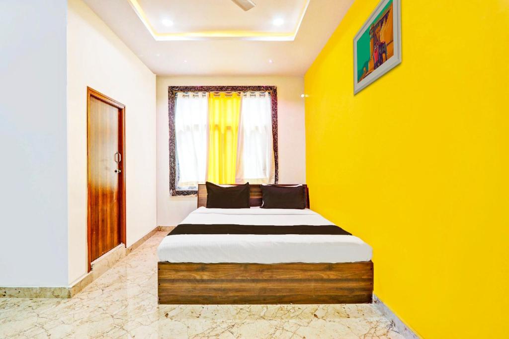 a bedroom with a bed in a yellow wall at Super Hotel O Stayo in Patancheru